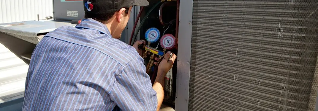 HVAC technician servicing a condenser unit in Burley